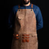 Leather apron in mocha color with cross-back straps, pocket, towel ring, and tool holders. Handmade from 100% genuine Italian leather. Perfect for BBQ, barbers, craft makers, and more. Customizable with your logo. Worldwide shipping available.