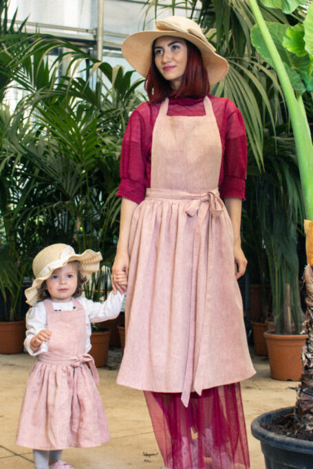 Elegant pinafore country style linen apron in baby pink color with tied neck and waist straps. Breathable and ideal for all-day wear, for kids and adults.