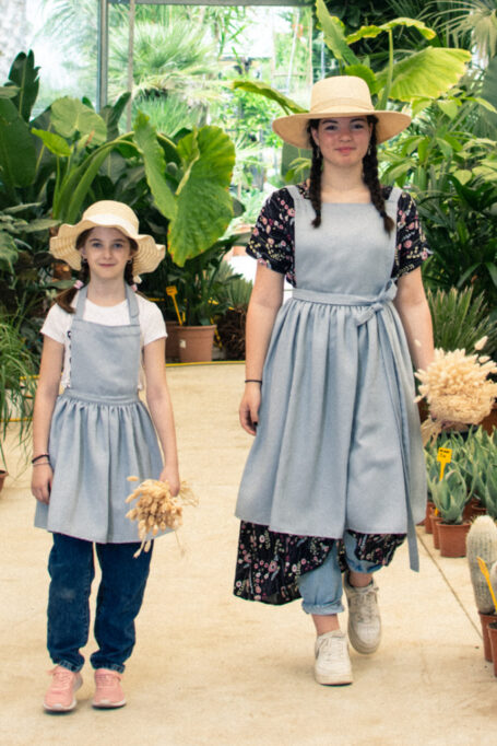 Elegant pinafore country style linen apron in light blue color with tied neck straps. Breathable and ideal for all-day wear, for kids and adults.