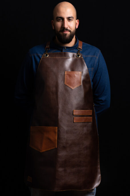 Elevate your workwear with our premium leather apron, crafted from durable cow leather. Adjustable cross-back straps with a customizable logo on the 'X' area for a personalized touch. Ideal for professionals in bars, restaurants, cafeterias, and butchers. Features a small chest pocket and a spacious waist pocket for added convenience. Discover style and comfort in this apron for men and women. Perfect for those who seek a blend of fashion and functionality. Shop now for a unique and personalized work accessory.