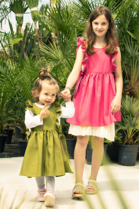 Beautiful and delightful kids’ pinafore aprons in two different colors, with adjustable waist straps and ruffle shoulder design for extra style.