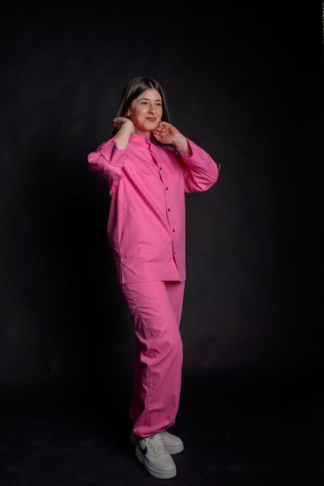 Happy young lady wearing her comfortable custom chef coat, with matching loose fit baby pink pants.