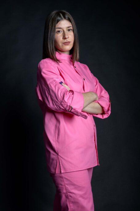 Woman wearing pink shirt with multiple details. Stylish workwear for everyday use.