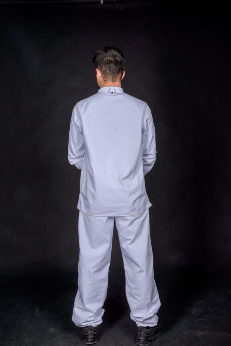 Man wearing stylish work clothes, his shirt supported with metal bronze stud button on neck and matching baggy pants for customizable use.