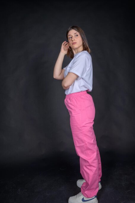Woman wearing her custom baby pink baggy pants with a white t-shirt.