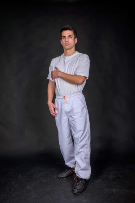 Chef wearing his street style loose fit pants, with adjustable elastic ankle cuffs and two front-side pockets, made from medium weight durable and breathable white fabric.