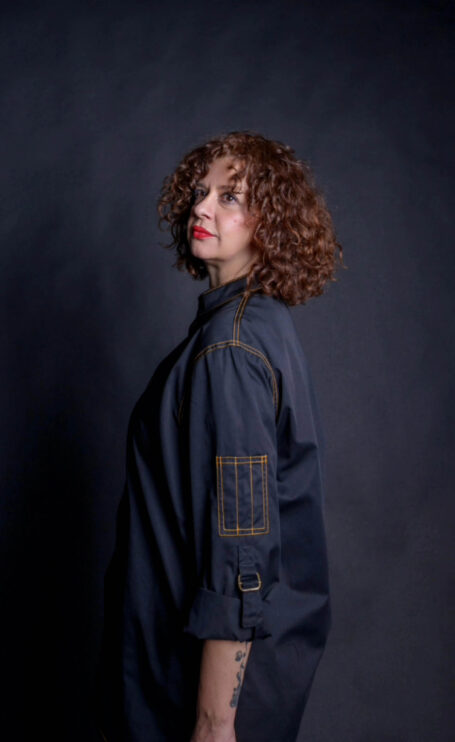 Custom chef coat with multi purpose options. Woman wearing chef jacket with two small pockets on both sleeves.