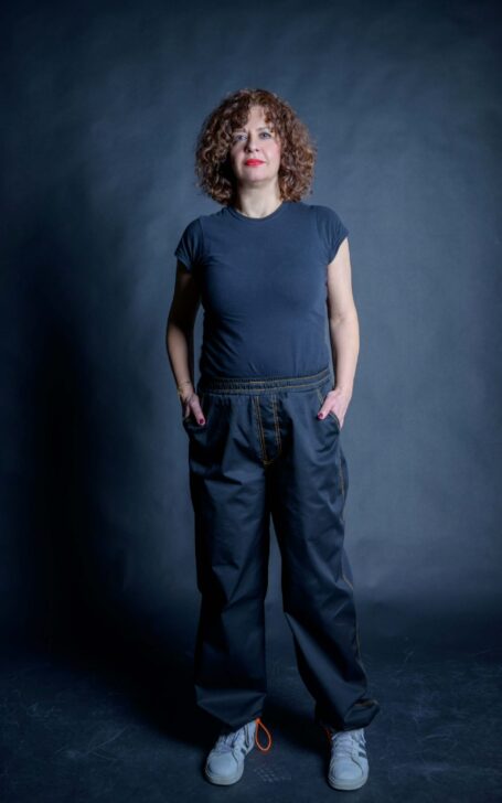 Customizable black pants with two front-side pockets and adjustable elastic ankle cuffs. Craft maker wearing a black t-shirt and her stylish workwear pants which can be worn as street style pants as well.
