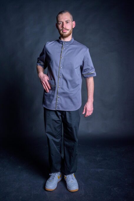 Comfortable and durable old school barber clothes in black background. Hairdresser wearing his fashionable gray barber shirt with black pants.