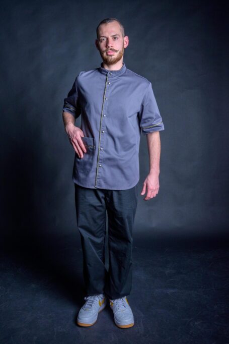 Comfortable and durable old school barber clothes in black background. Hairdresser wearing his fashionable gray barber shirt with black pants.