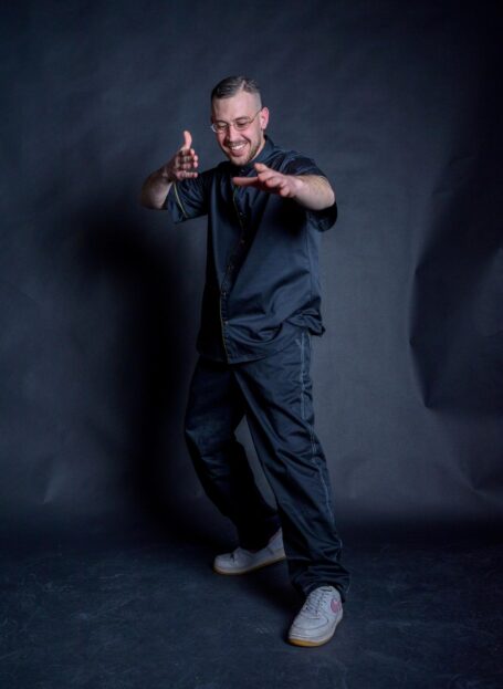 Happy man wearing a comfortable set of barber clothes in black color. Barber smock with matching baggy pants.