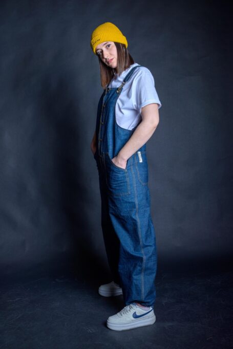 Barista wearing her stylish loose fit overall pants, made from durable blue denim fabric.