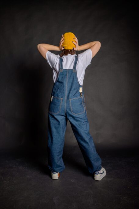 Florist wearing a unisex blue denim salopette with two back pockets and a metal bronze hook.