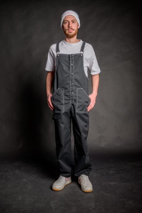 Florist wearing a baggy salopette, with metal stud buttons and dungaree metal clip fasteners.