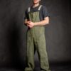 Barista wearing comfortable unisex streetwear salopette, which has adjustable cotton beige straps with dungaree metal clip fasteners.