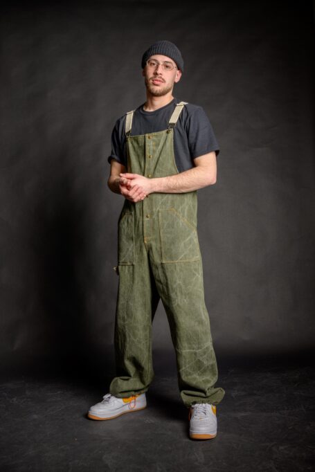 Barista wearing comfortable unisex streetwear salopette, which has adjustable cotton beige straps with dungaree metal clip fasteners.