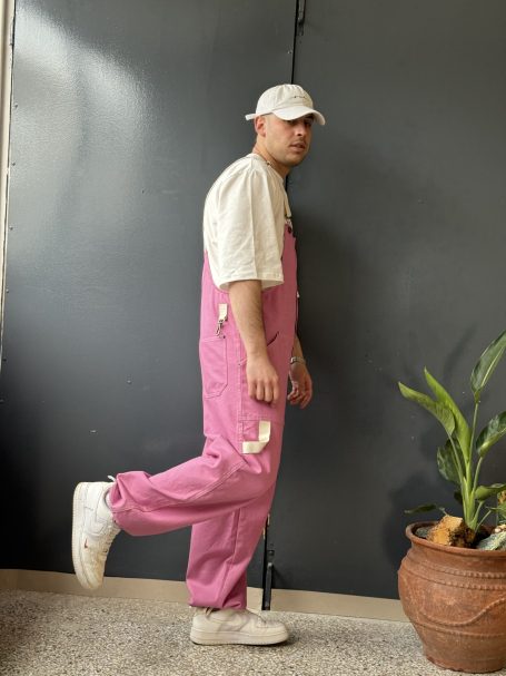 skater wearing the pink overall pants loose fit with beige details and white shoes