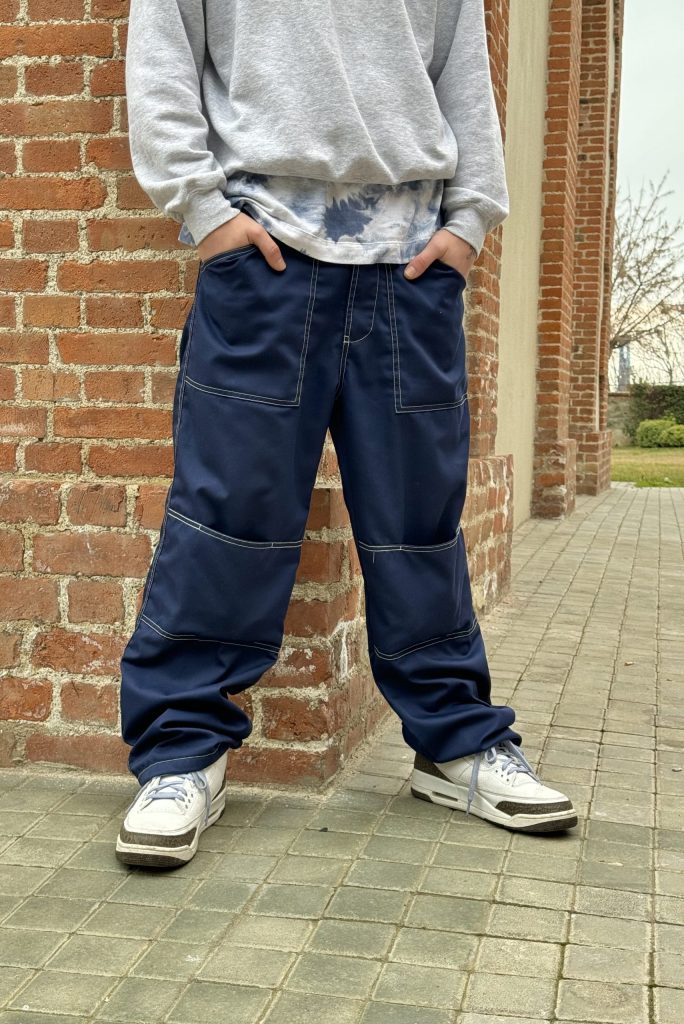 Blue baggy pants for men with white contrast stitching and loose fit.
